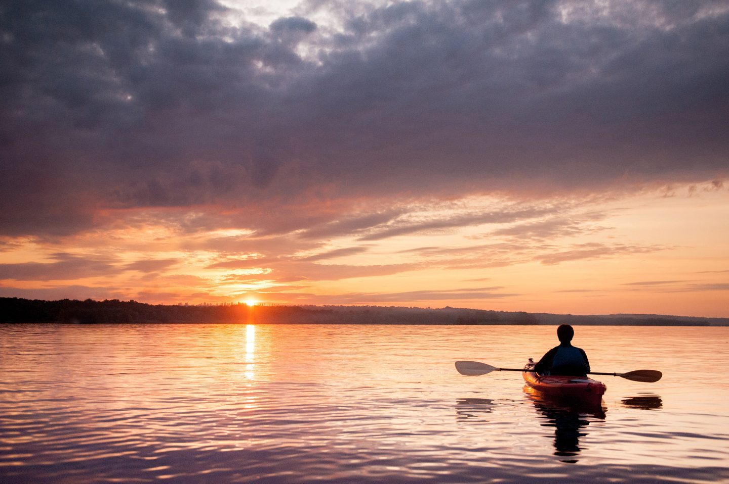 Kayaker paddling at sunset