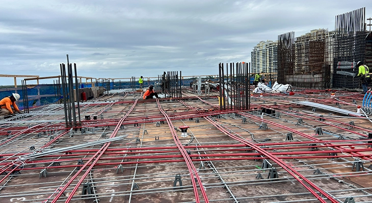 Workers installing conduit and rebar across a large slab deck.