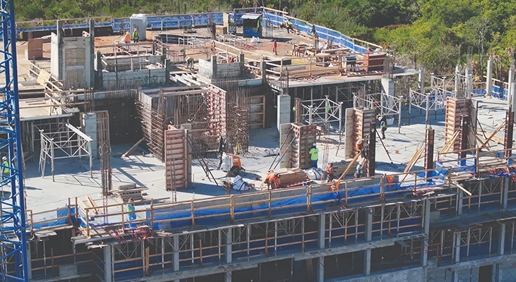 Workers forming concrete walls and columns on an upper construction level