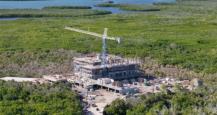 Aerial view of a coastal building under construction with a crane.