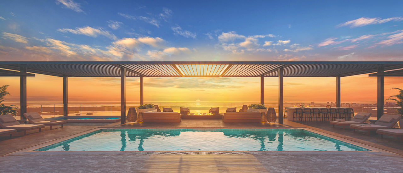 Rooftop infinity pool with lounge seating and ocean sunset view.