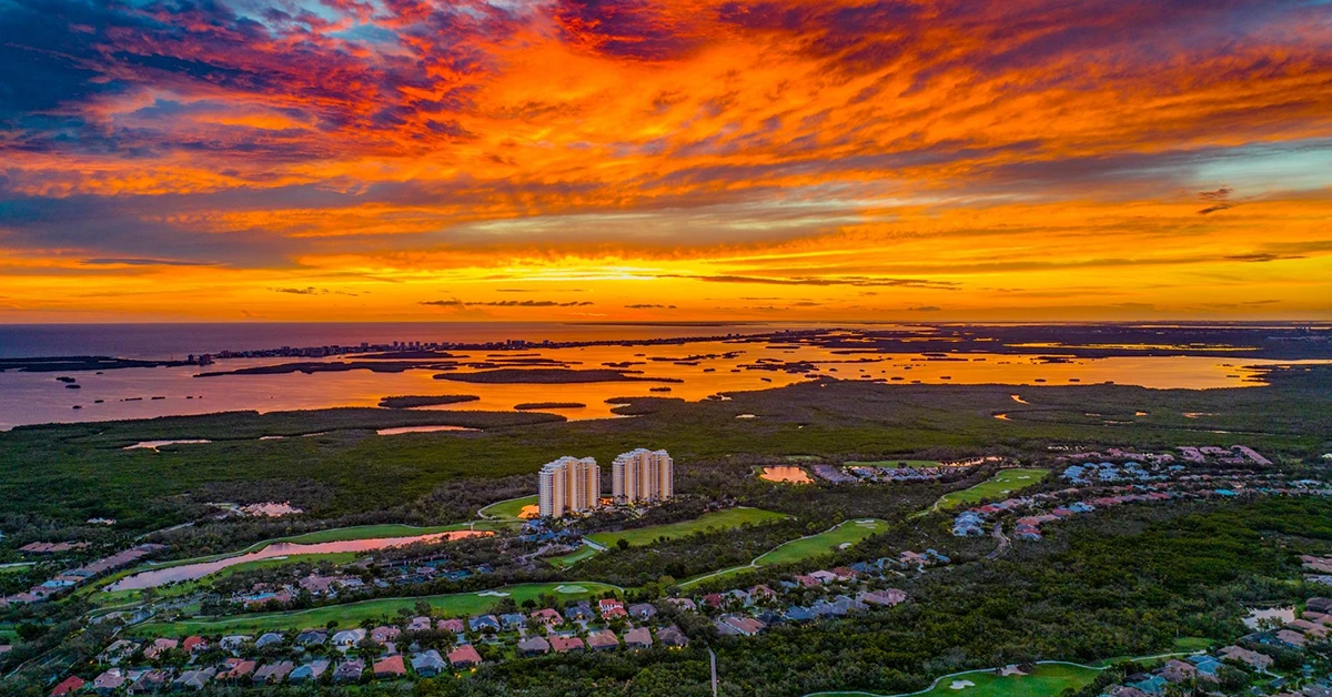 Aerial sunset view over Estero waterways, golf courses, and residential communities in Southwest Florida.